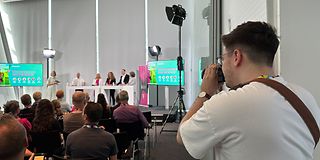 A trainee films speakers on the stage
