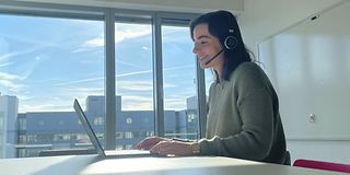  Volunteer sits at the desk with her laptop and conducts a virtual interview