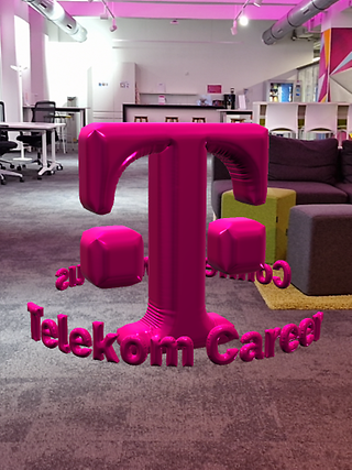 In a office, the T logo floats between furniture as an AR object with a balloon effect in the middle of the room