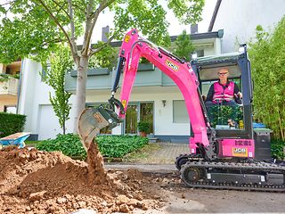 Vorstandsvorsitzender Tim Höttges bedient einen magentafarbenen Bagger.