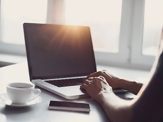 Laptop, Handy und Kaffeetasse auf dem Tisch