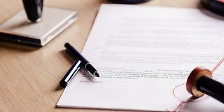 Blatt mit Stift und Stempel auf Tisch