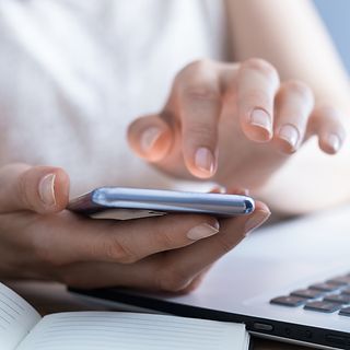 A hand tiping a telephone number.