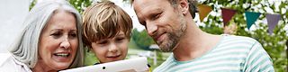 Großmutter, Vater und Sohn am Tablet-Computer.